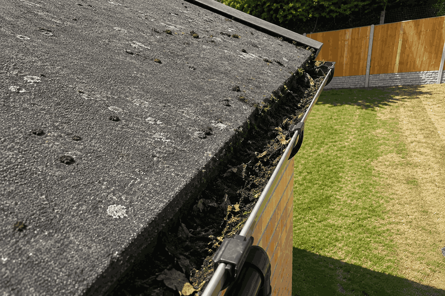 Before autumn gutter cleaning - roofline clogged with wet fallen leaves and compost